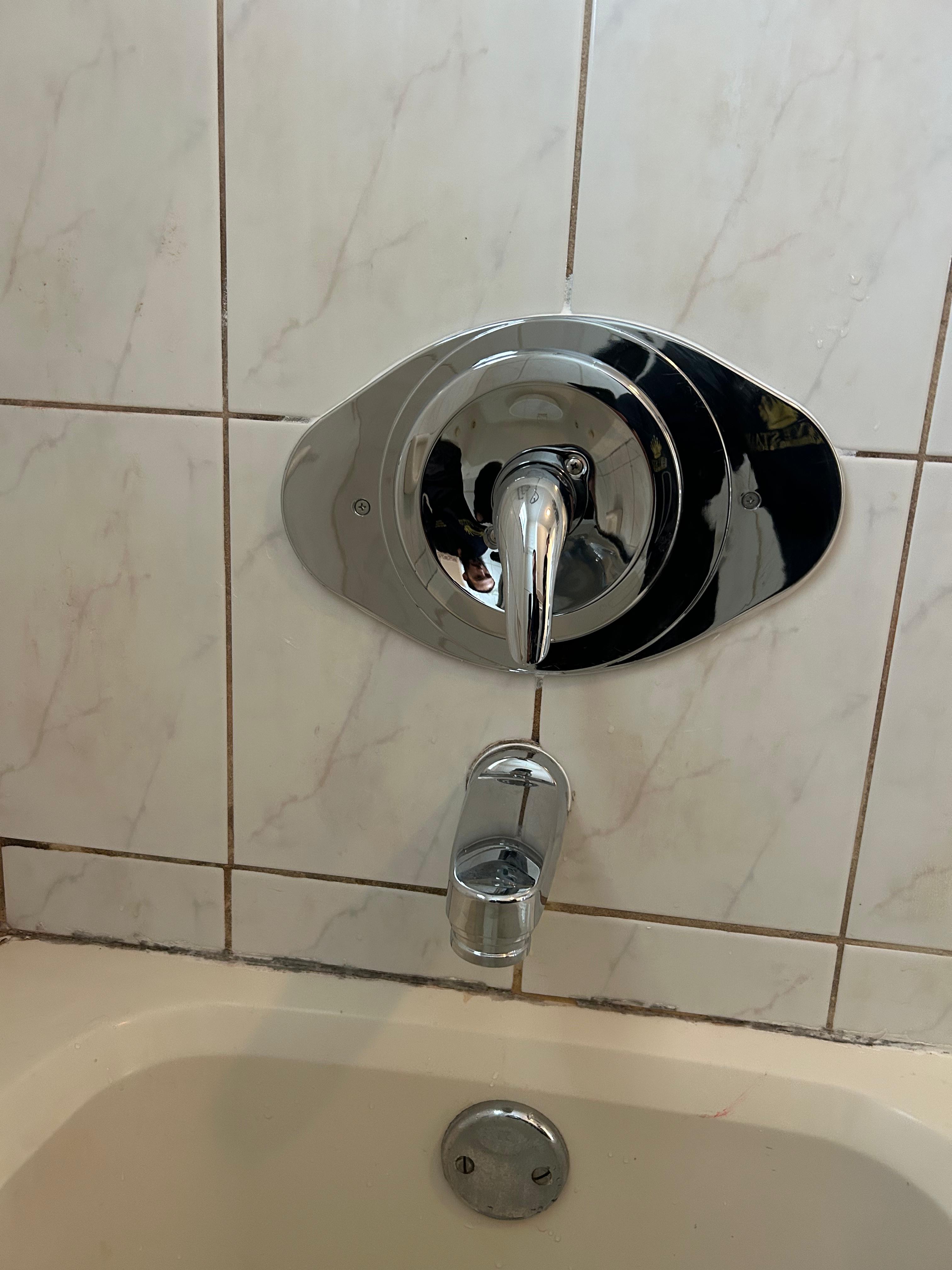 Chrome bathtub faucet installation on marble tile wall